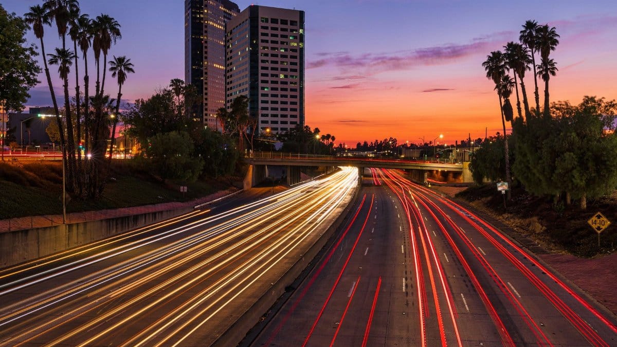 Vibrant sunset view of Burbank highway, palm trees, and light trails creating a dynamic urban scene.