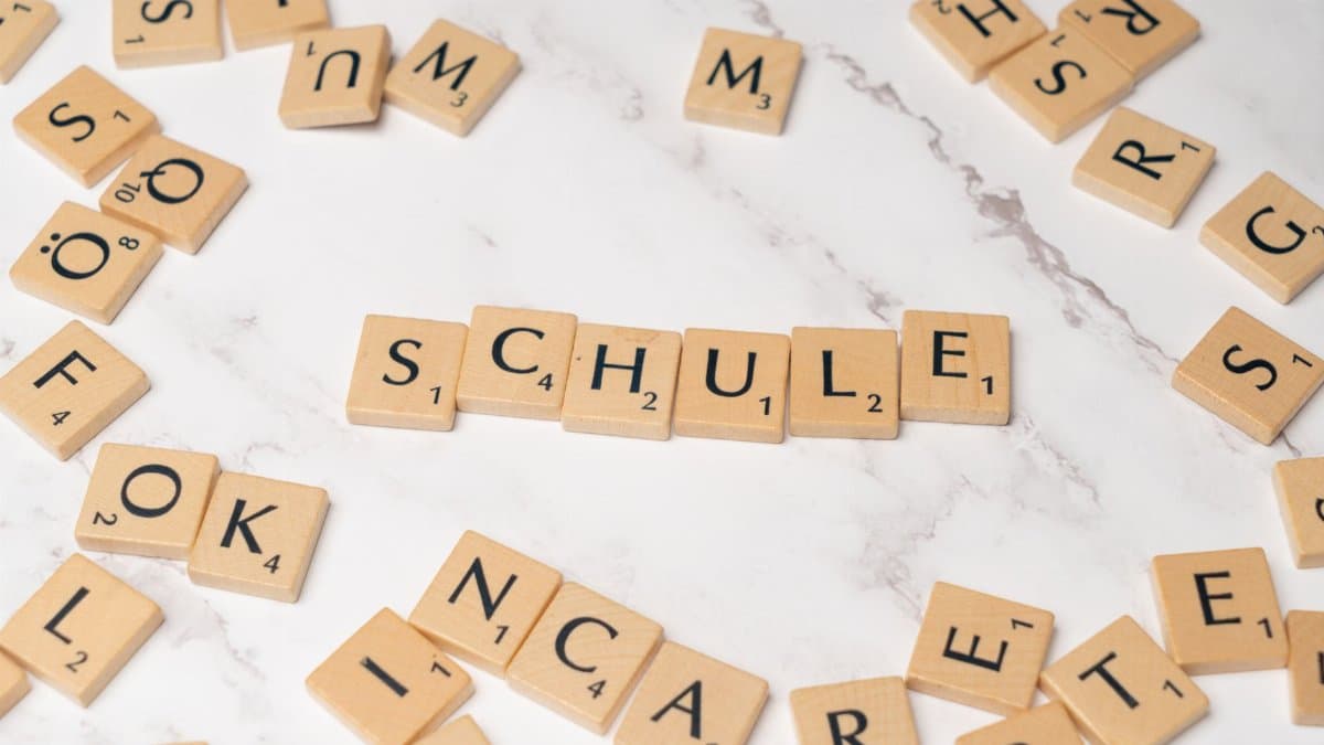 Scrabble letter tiles spelling 'Schule' on a marble surface, ideal for language learning concepts.