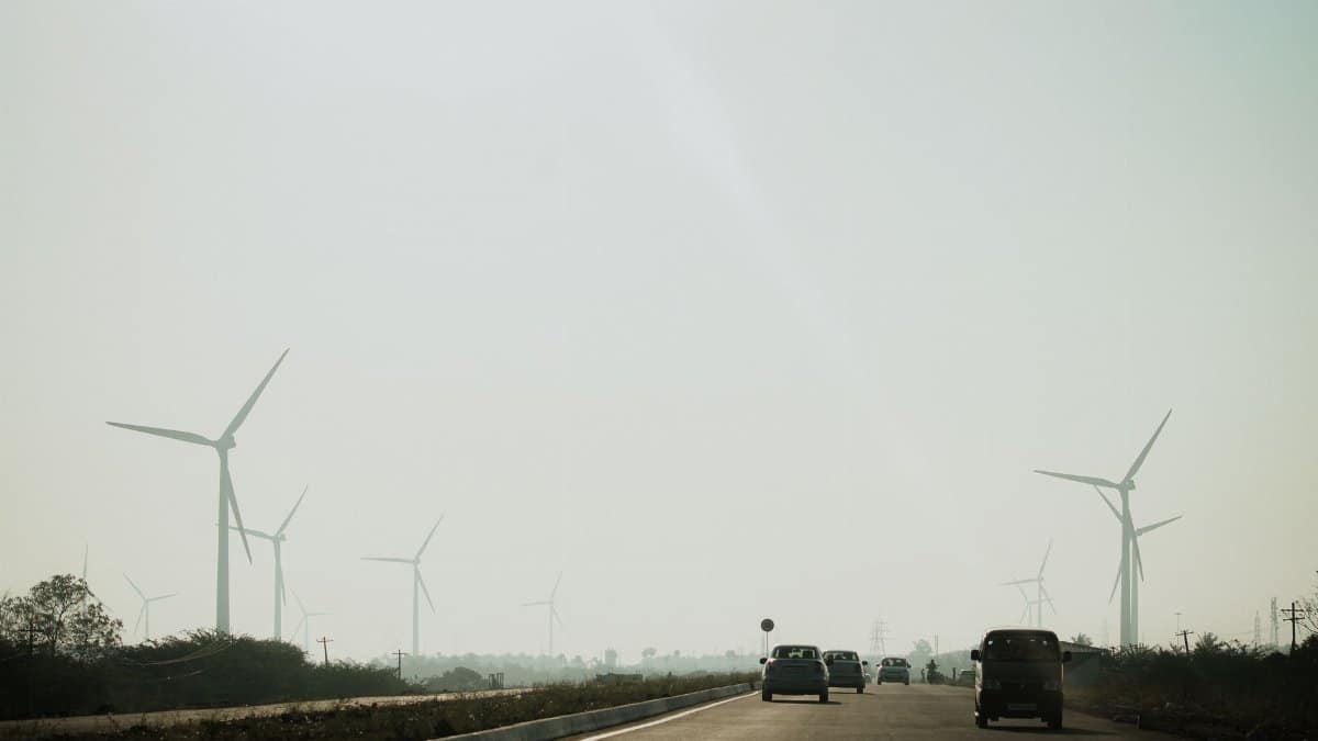 A highway scene with cars and tall wind turbines under a clear sky, illustrating renewable energy.