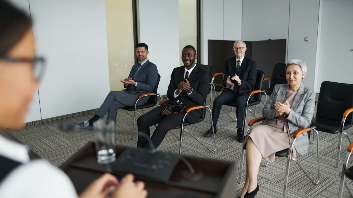 A diverse group of business people clapping in a conference room setting.