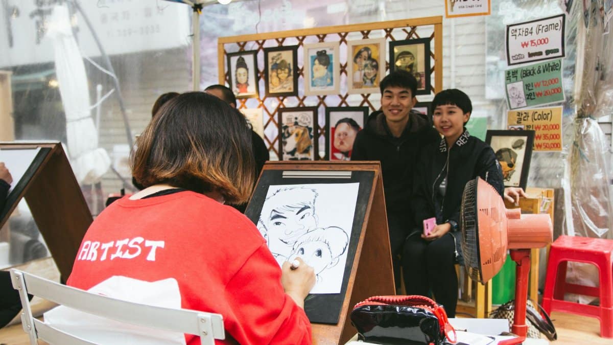 Street artist drawing a caricature for a couple at an outdoor art booth. Vibrant and lively scene.