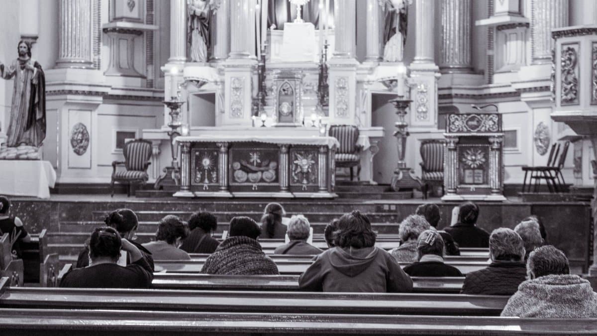 A grayscale image depicting people seated in a church interior, focusing on spirituality and worship.