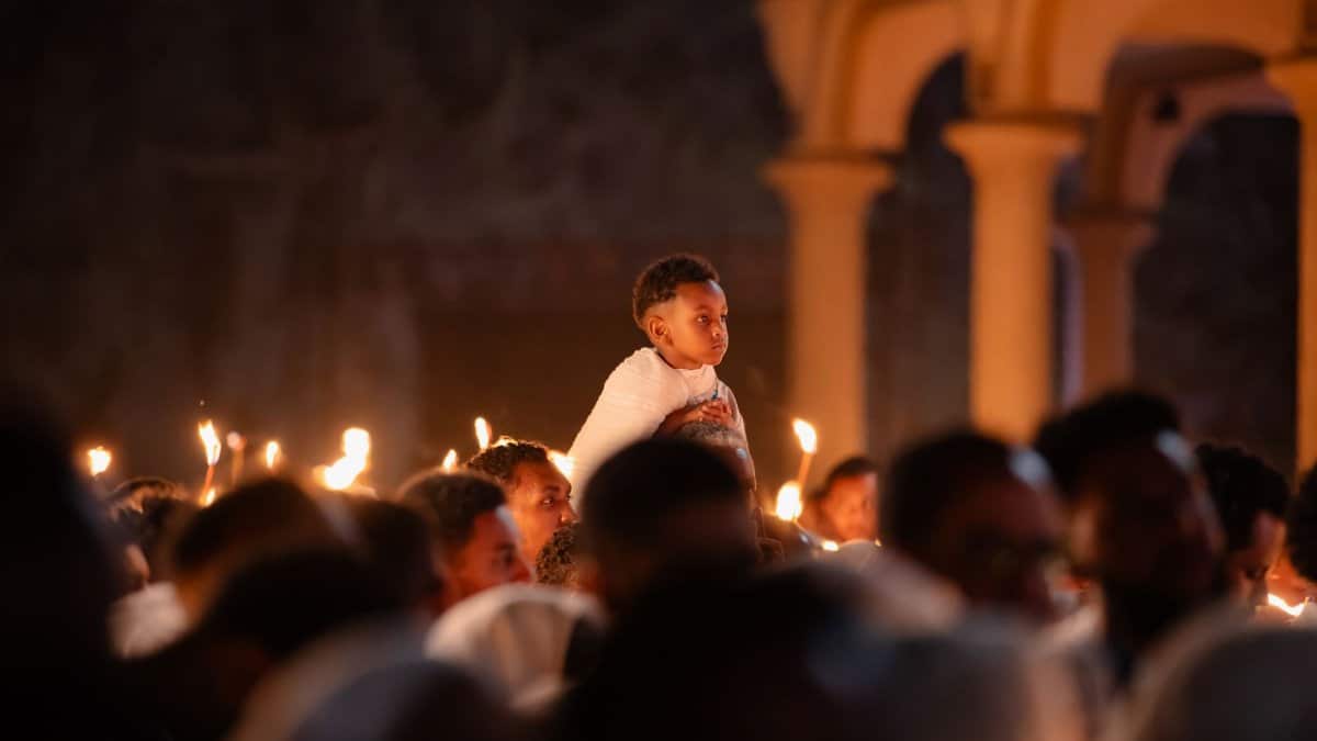 A boy on shoulders during a candlelit service at an Ethiopian church.