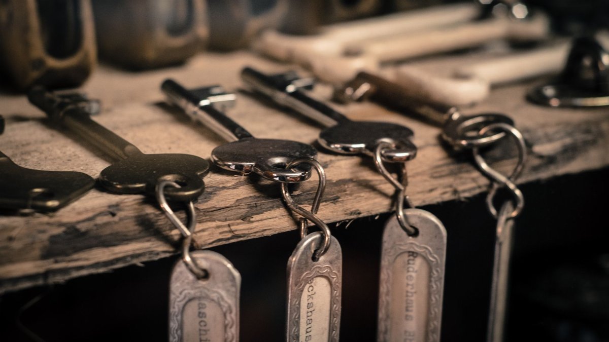 A detailed shot of antique metal keys with keychains hanging on a rustic wooden surface.