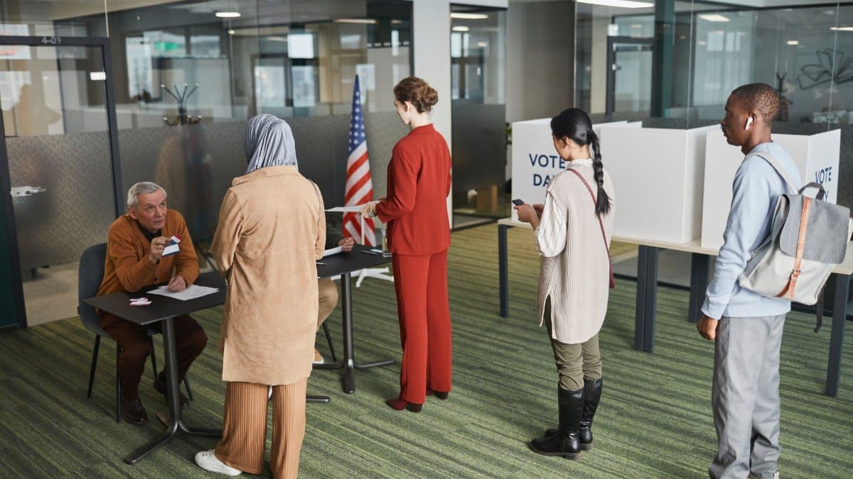 Diverse group of voters lining up at an indoor polling station on election day.