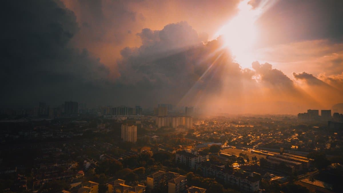 Captivating aerial view of a cityscape under a dramatic sunset, with sunrays breaking through clouds.