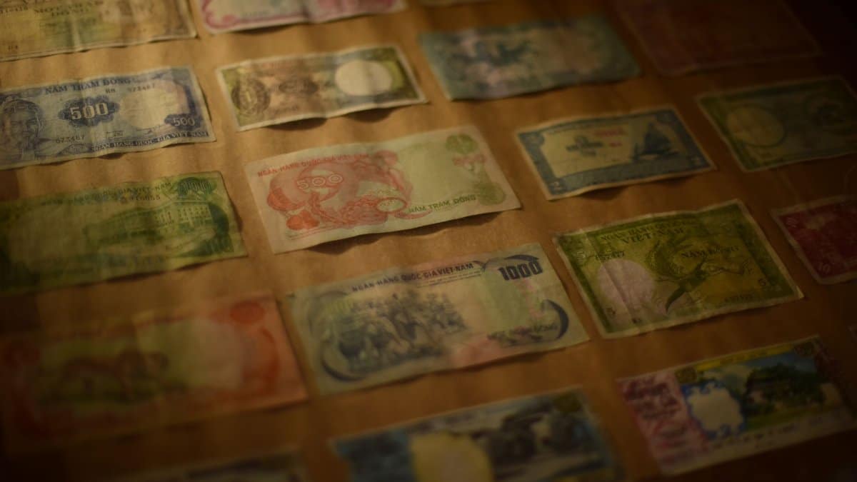 Close-up of various vintage Asian banknotes in a collection display under warm lighting.