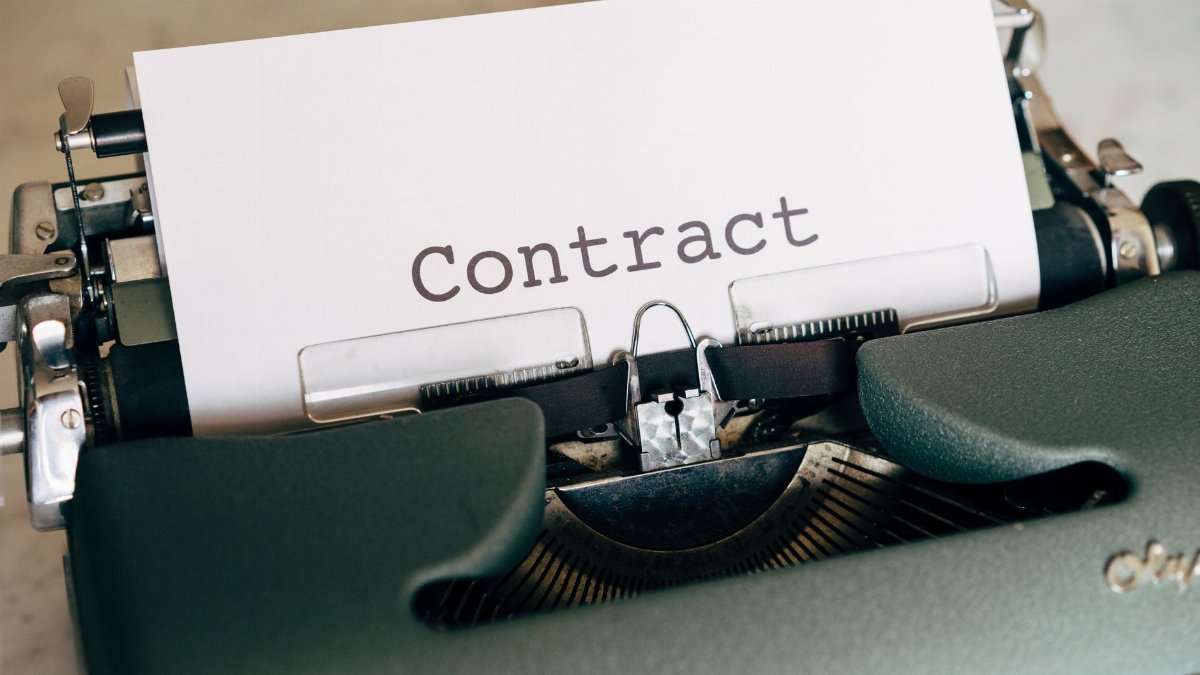 A close-up of a vintage typewriter with a typed contract page.