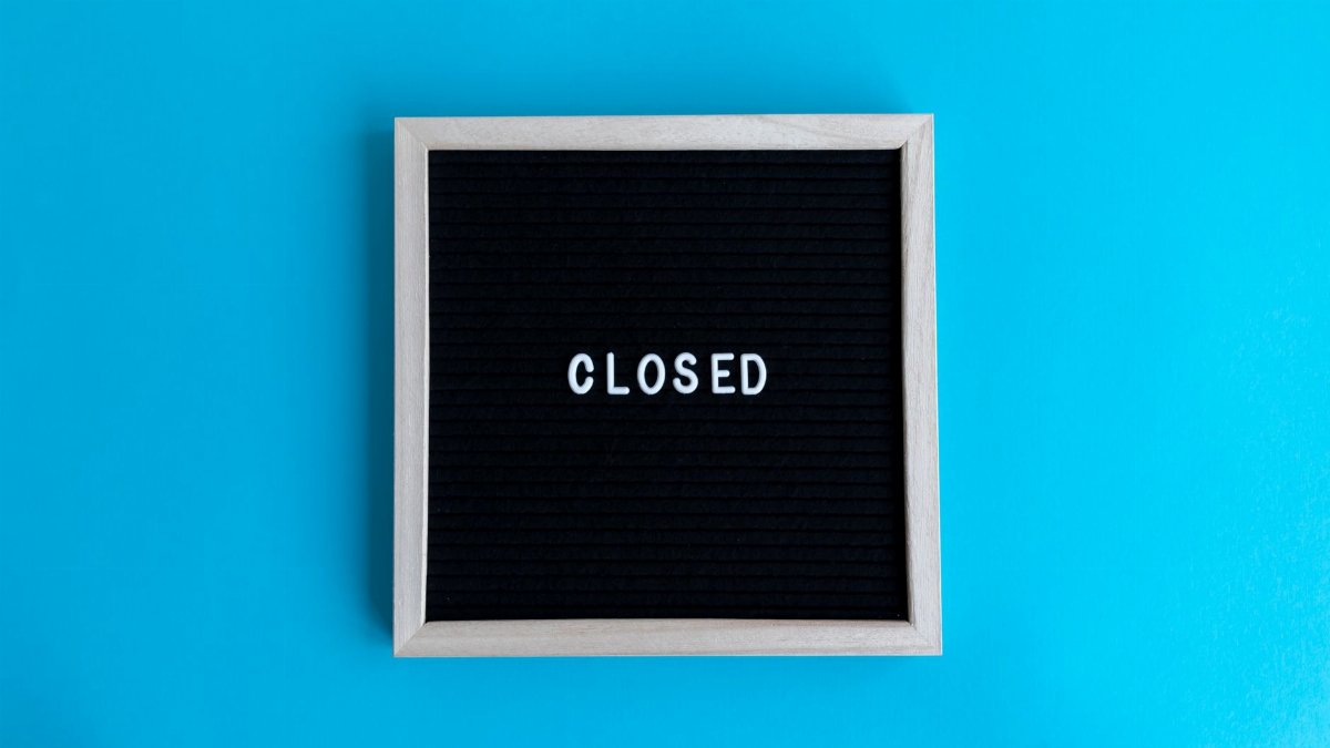 A letter board with 'Closed' displayed against a vibrant blue backdrop, signifying a closure or notice.