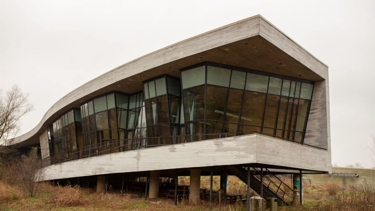 Contemporary building with a curved glass facade and concrete exterior amidst a natural setting.