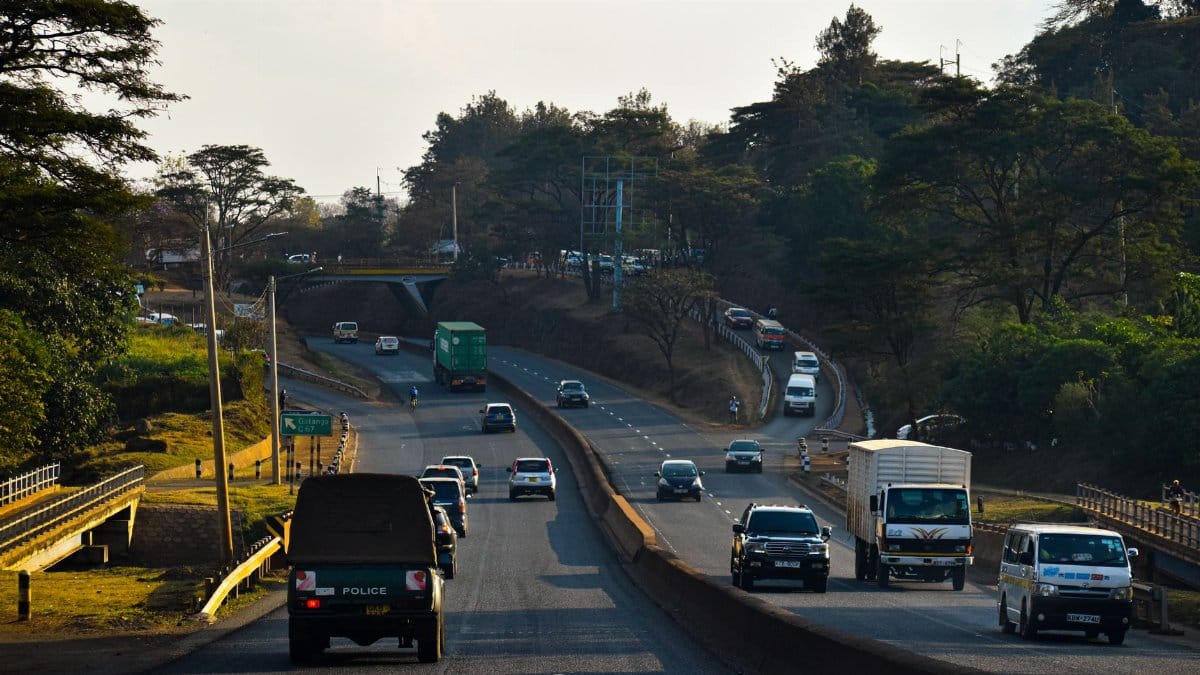 Dense traffic on a Nairobi highway surrounded by lush greenery during the day.