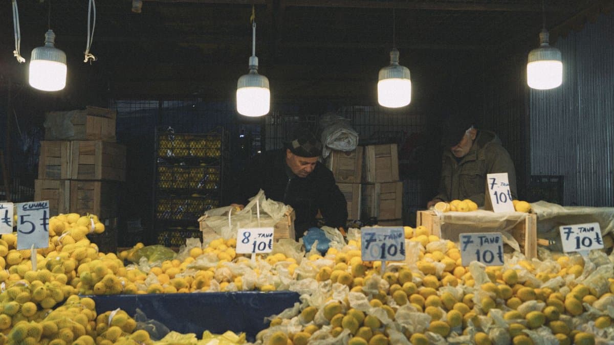 Street vendors selling lemons at an outdoor market stall under hanging lamps.