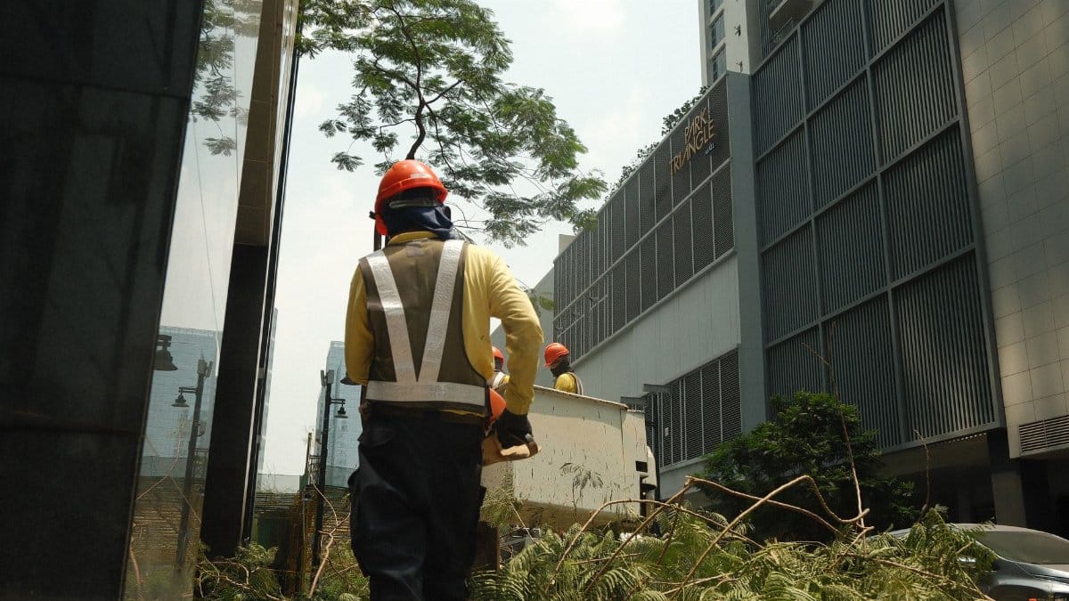 Construction workers in safety gear clearing debris on a sunny day in a Philippine city.
