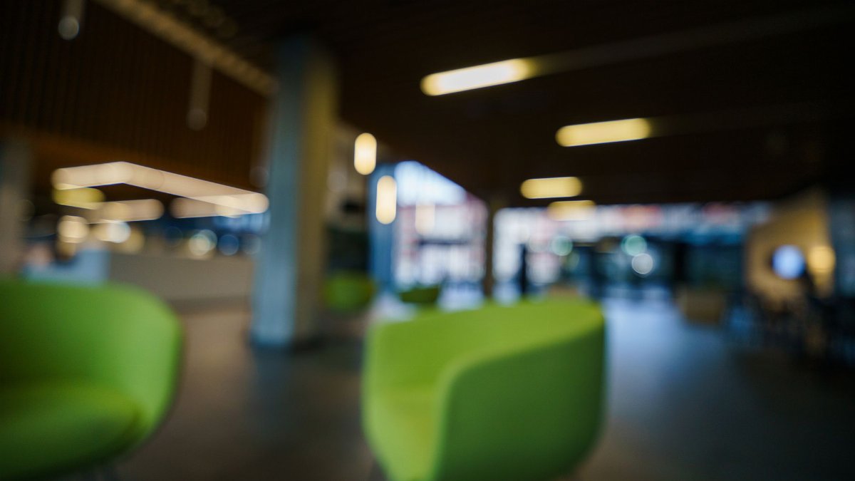 Contemporary office lobby with green chairs and blurred lighting, creating a modern and abstract look.