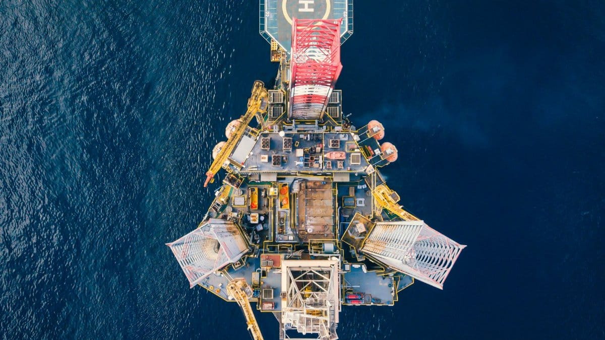 High-angle view of an offshore oil platform with helipad surrounded by deep blue ocean.