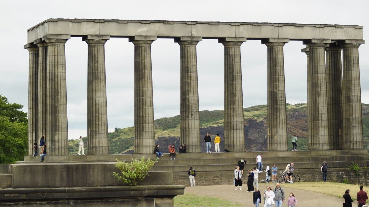 Tourists explore the National Monument of Scotland, an iconic Edinburgh landmark resembling the Parthenon.