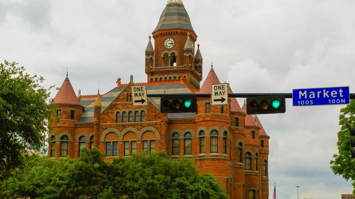 View of the iconic Dallas County Courthouse with its red brick facade and clock tower, capturing historic architecture.