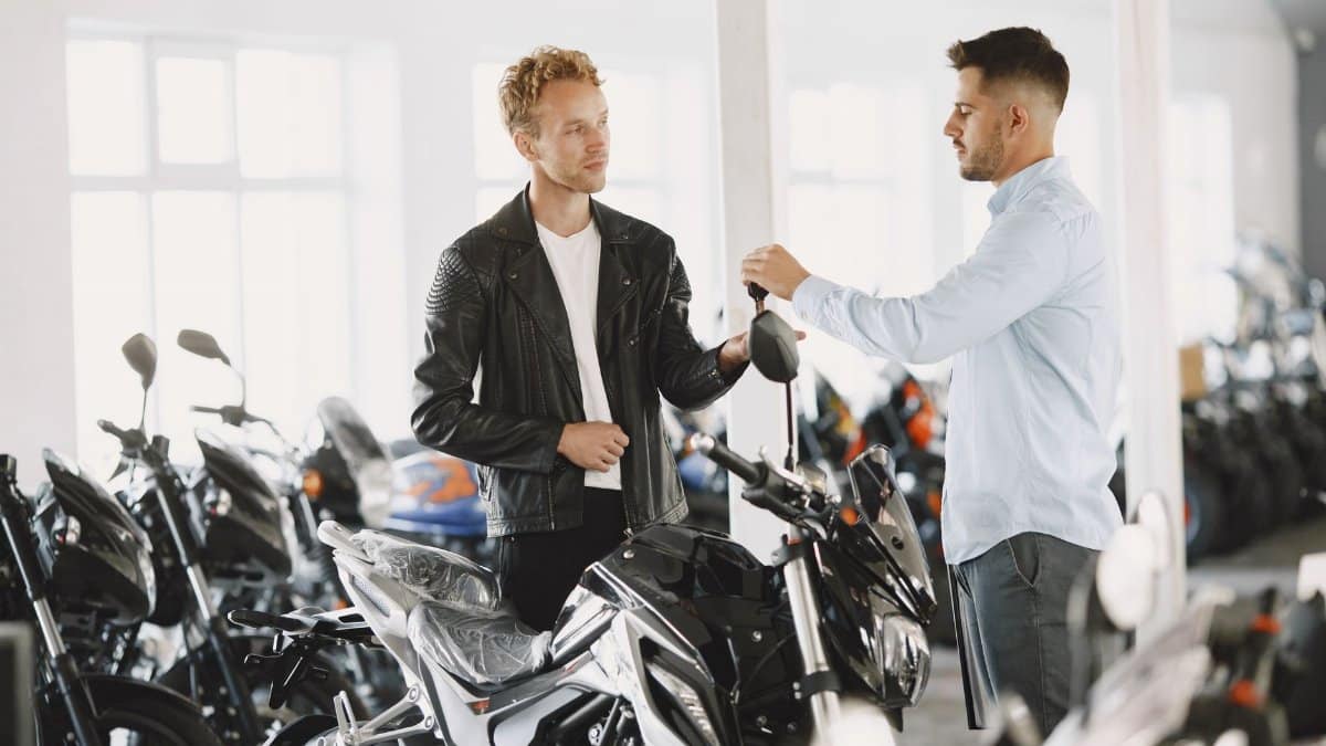Two men engaged in conversation in a motorcycle showroom, highlighting customer interaction.