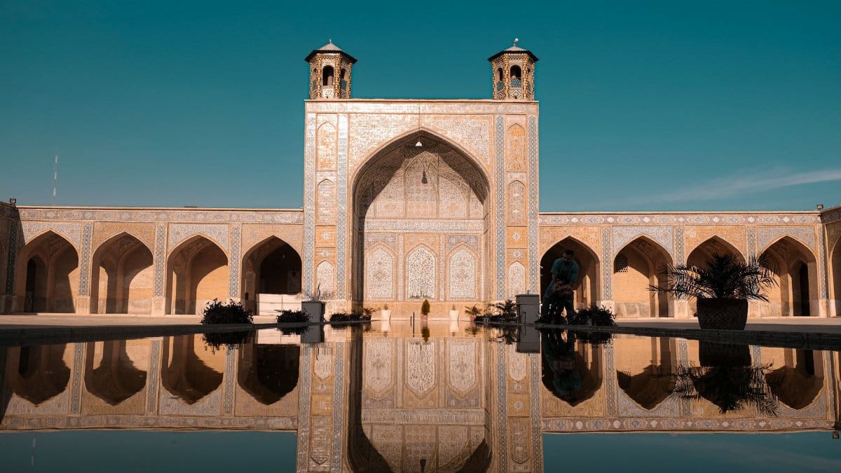 Beautiful reflection of Vakil Mosque's architecture in a pool in Shiraz, Iran. Capture the essence of Persian design.