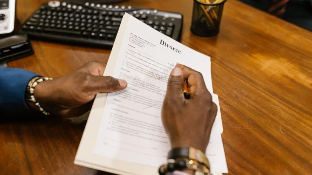 A person signs official divorce documents at an office desk.