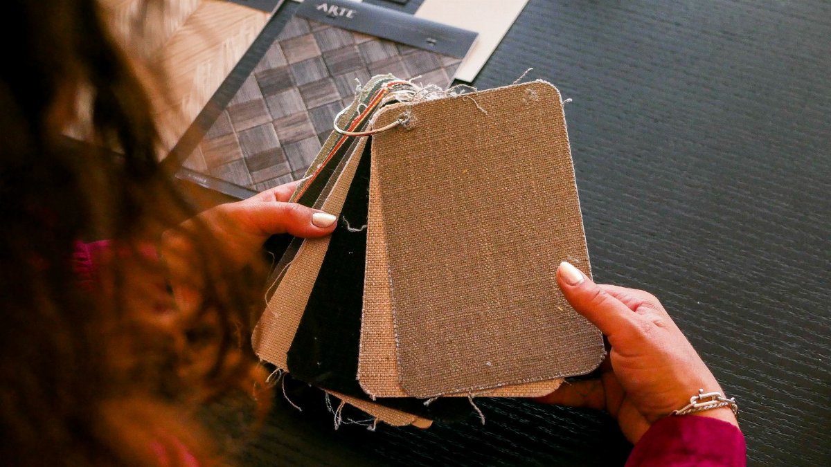 Designer examining fabric swatches for interior design on a black table.