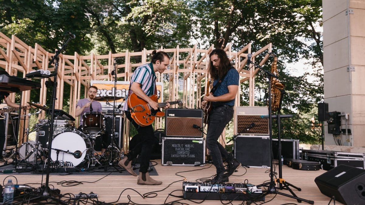 Live band playing on an outdoor stage with drums and electric guitars. Captivating performance.