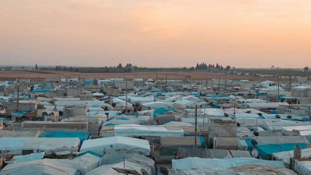 Aerial photo of a sprawling refugee camp under a vibrant sunset sky