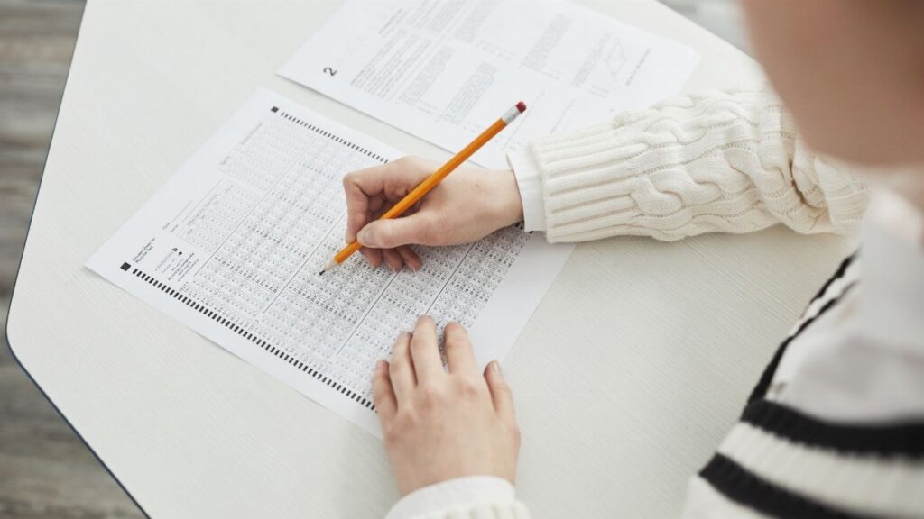 Close-up of a student filling out a multiple-choice exam in a quiet classroom setting.