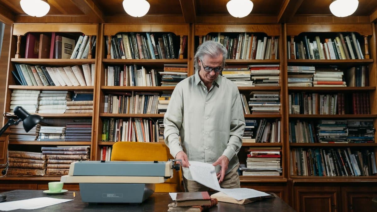 Elderly man browsing historical books in a well-stocked library, symbolizing knowledge.