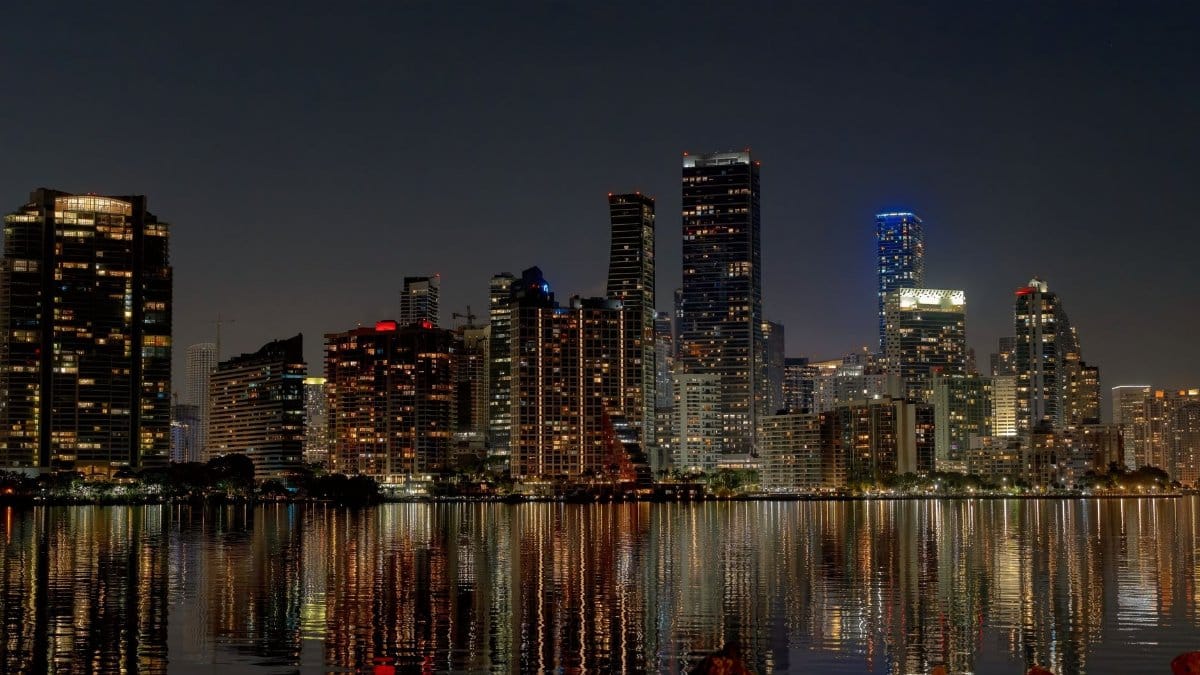 Explore the vibrant Miami skyline at night with stunning reflections in the water.