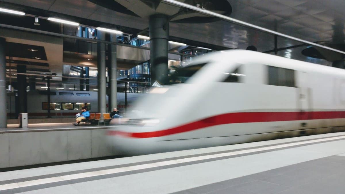 Blurred motion of a high-speed train departing from a modern urban station platform.