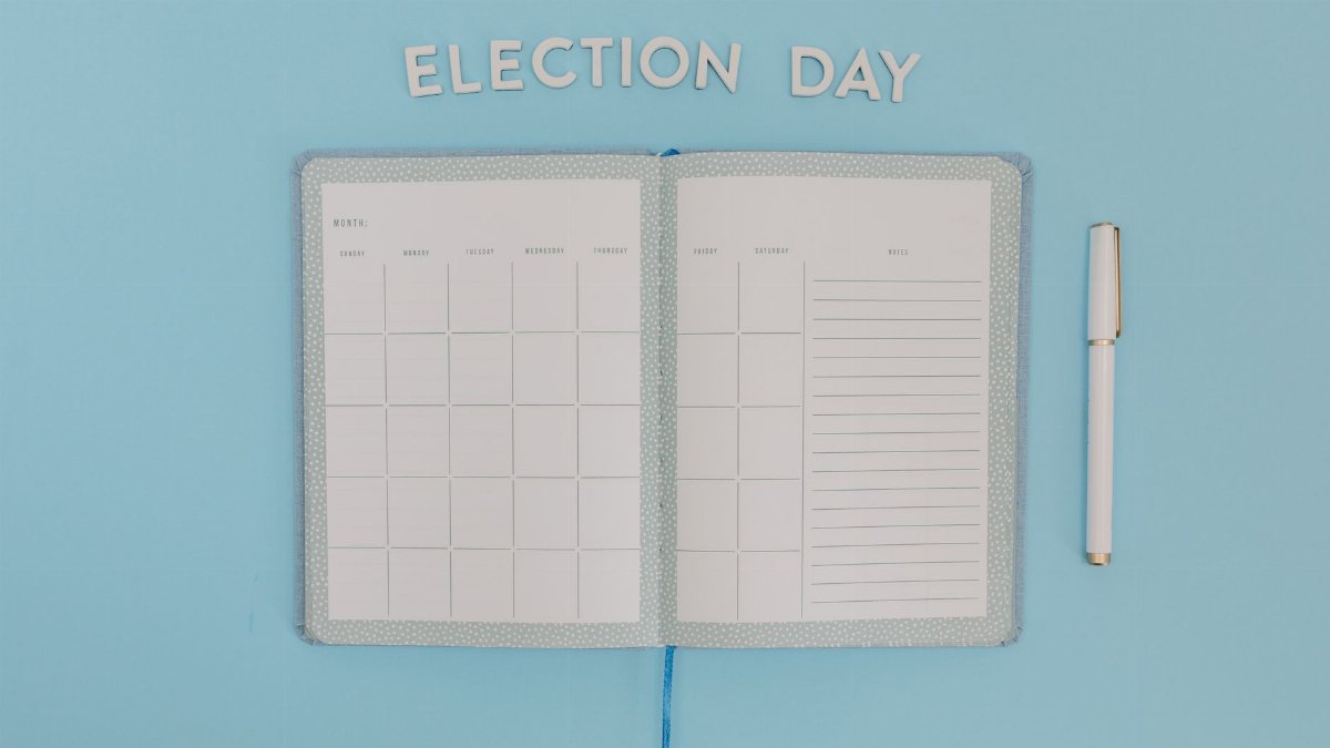 Open planner for Election Day on a bright blue background with a pen