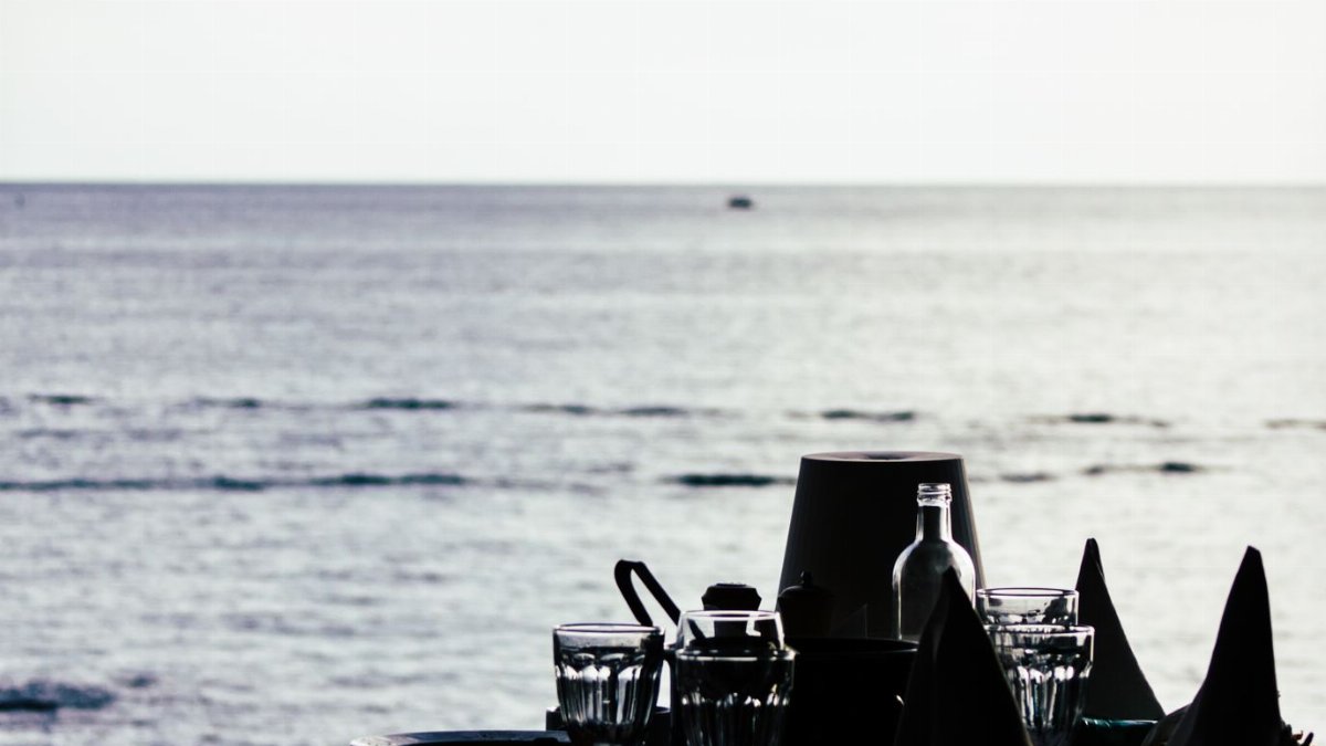Elegant silhouette of a dinner setting with ocean view, capturing a serene seaside atmosphere.