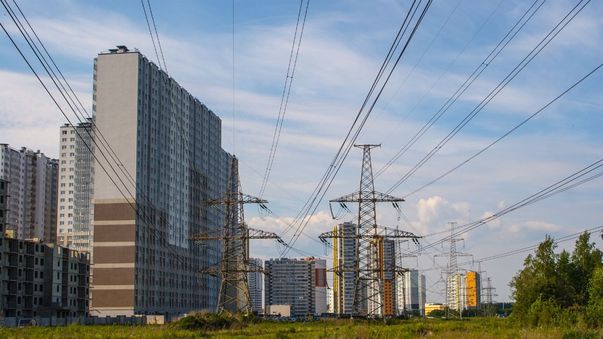Urban scene showcasing apartment buildings and electricity towers under a clear sky.