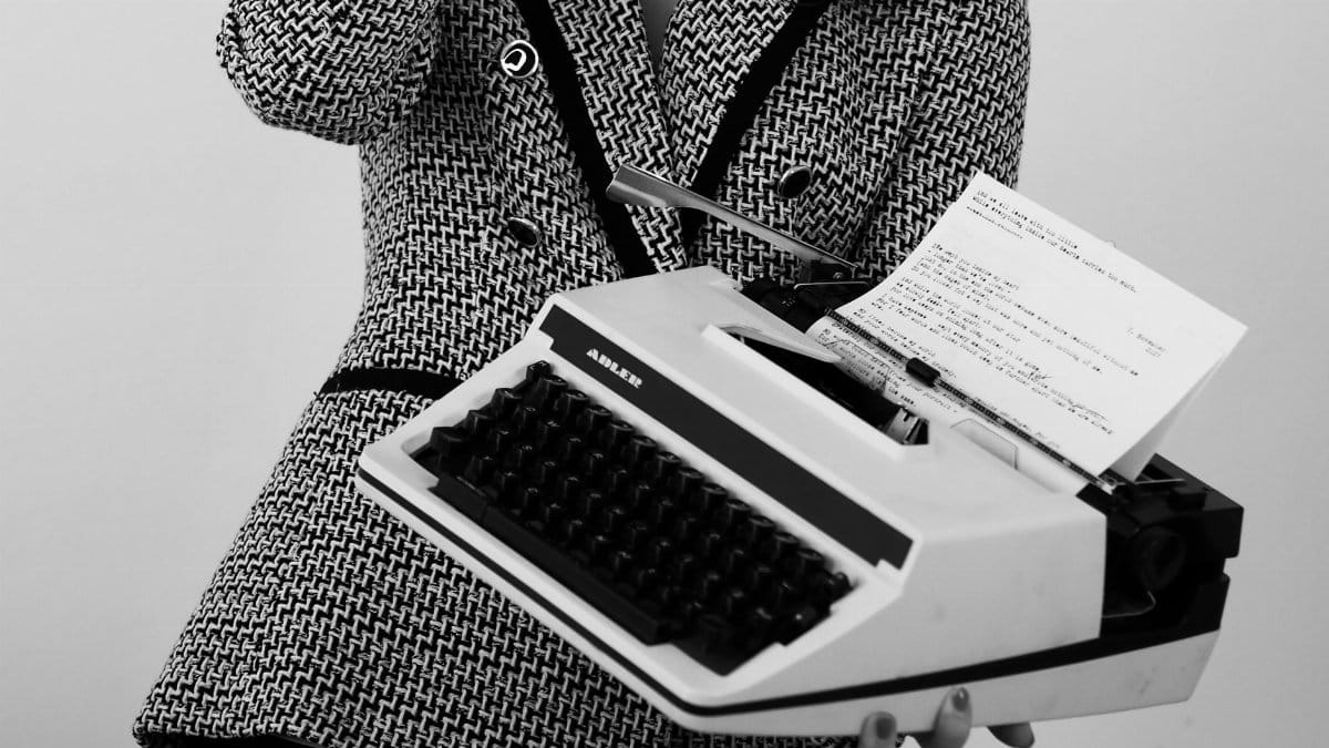 Elegant black and white portrait of a woman holding a vintage typewriter.