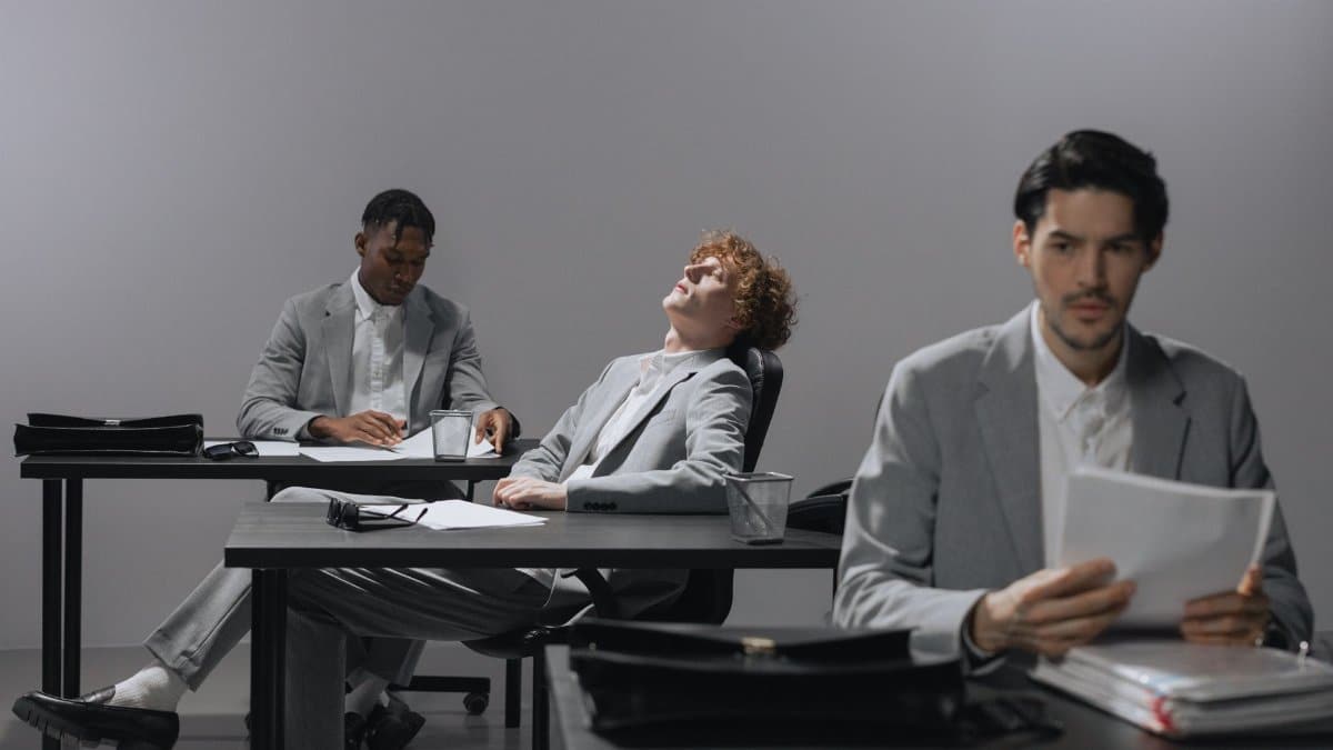 Professionals in gray suits engage in a business meeting at an office.