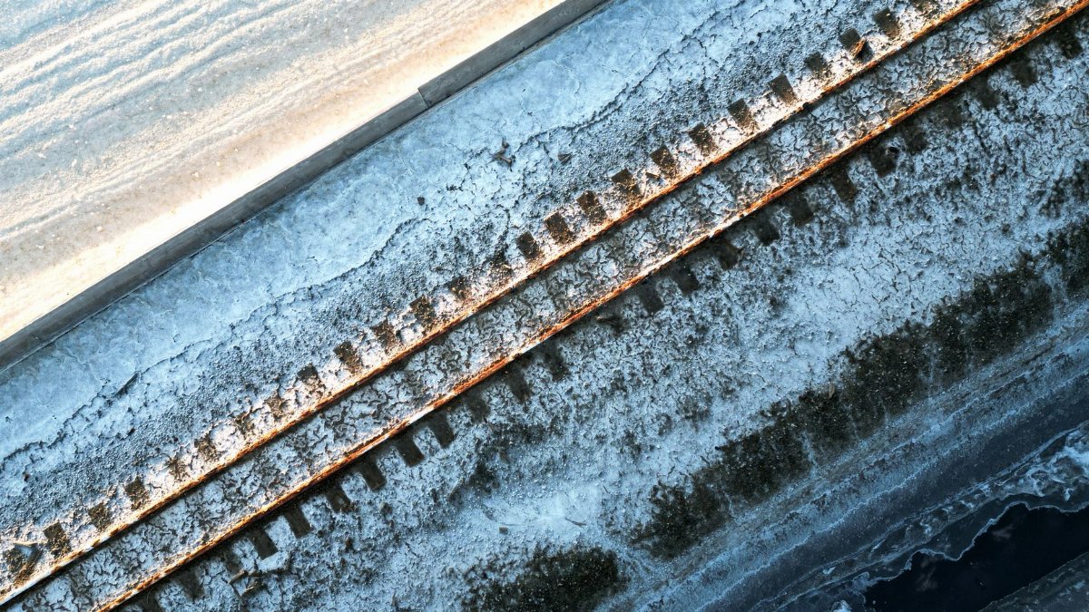 Aerial shot of railway tracks covered in snow, reflecting the cold winter season.
