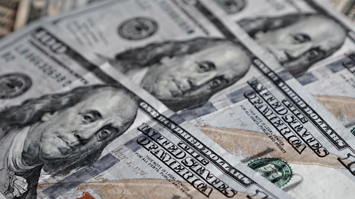 Detailed view of several US $100 bills showing Benjamin Franklin's face.