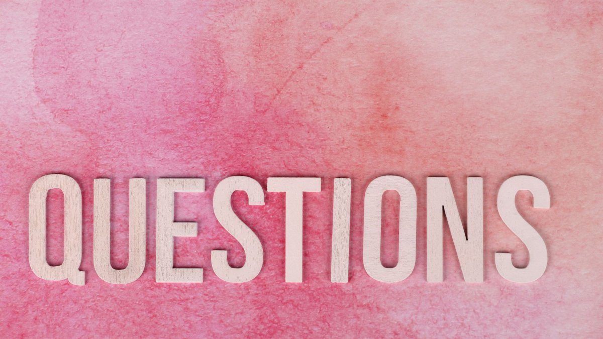 Wooden 'QUESTIONS' text on pink watercolor background, perfect for design and art concepts.