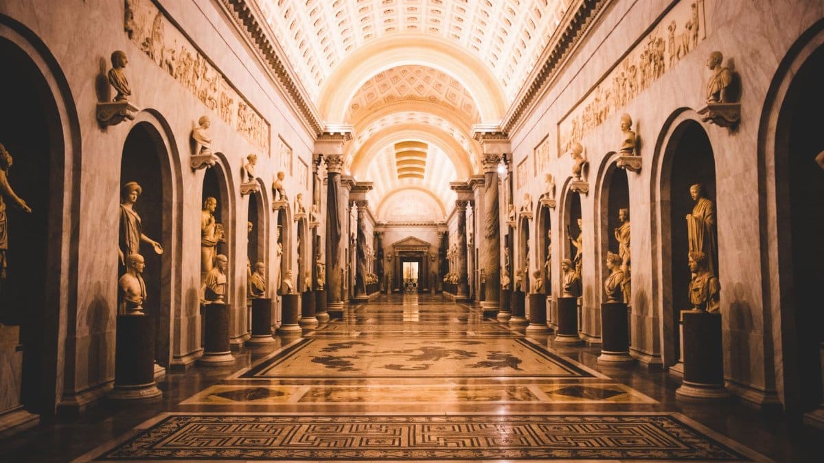 A stunning view of a hallway adorned with classical sculptures in the Vatican Museums.