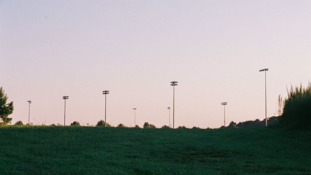 Serene sports field at dusk with silhouetted light poles under a pastel sky.