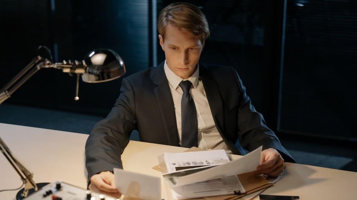 Focused investigator reviewing evidence in a dimly lit office setting.