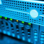 Focused view of a modern data server rack with blinking lights in a blue-lit environment.