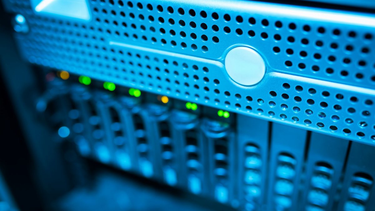 Focused view of a modern data server rack with blinking lights in a blue-lit environment.