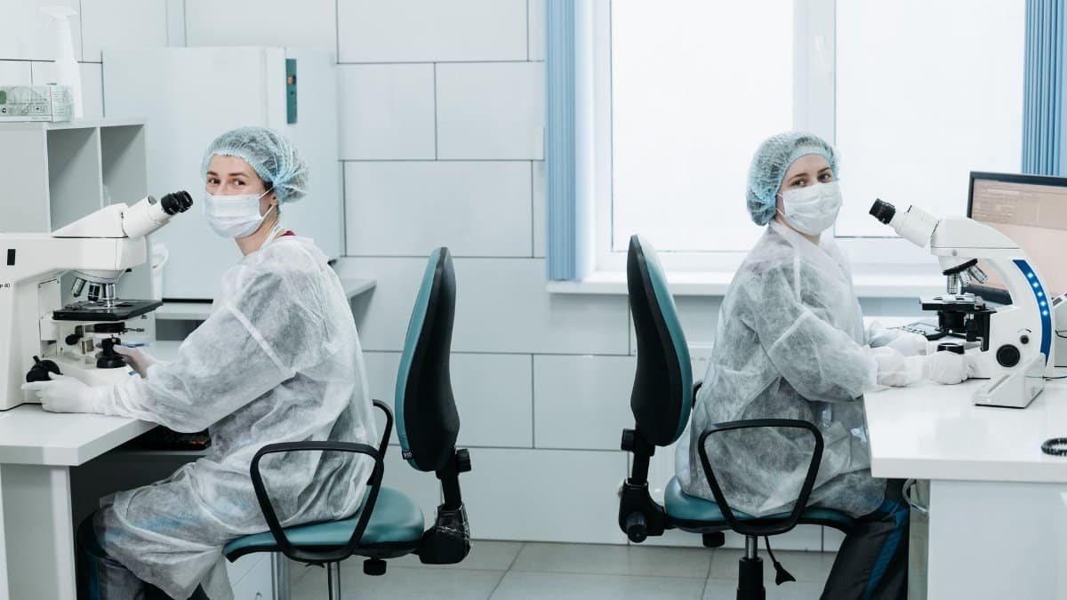 Two female scientists working with microscopes in a laboratory setting.