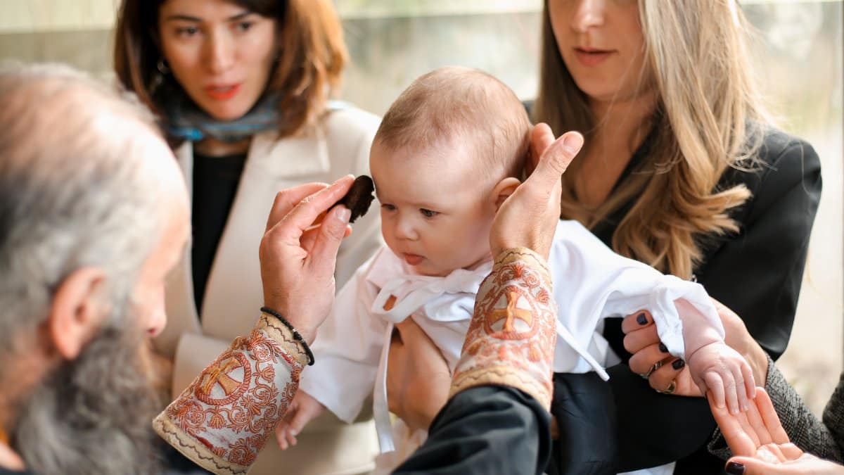 A touching moment during a baby's baptism, showcasing family and religious traditions.