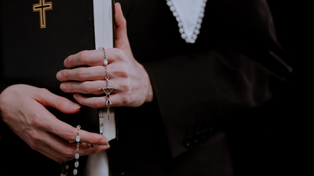 A close-up view of hands holding a rosary and a bible, symbolizing faith and prayer.