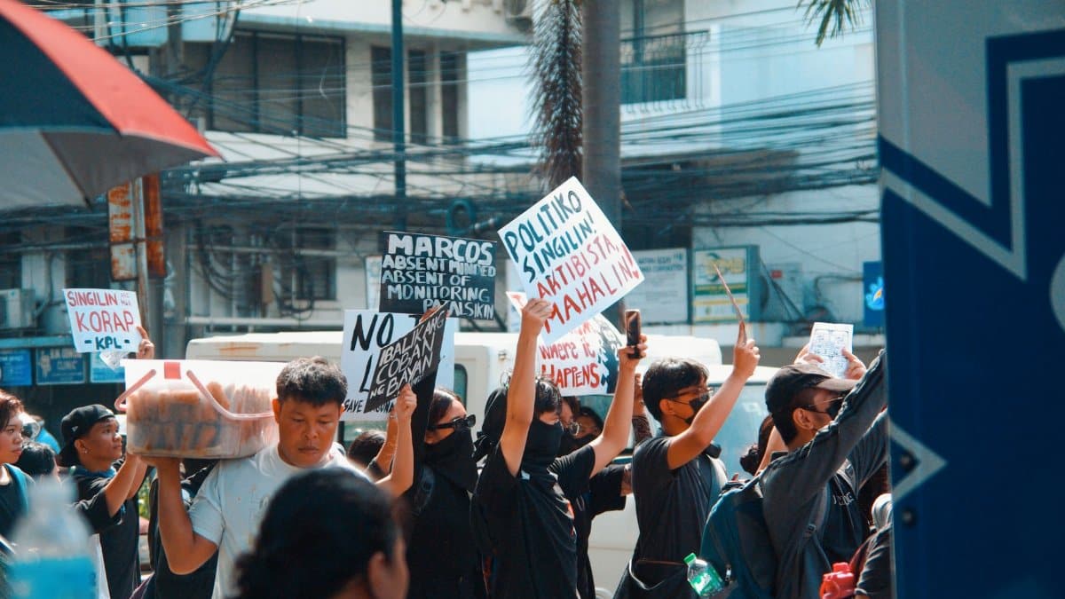 A vibrant urban protest scene with demonstrators holding signs, expressing political messages.