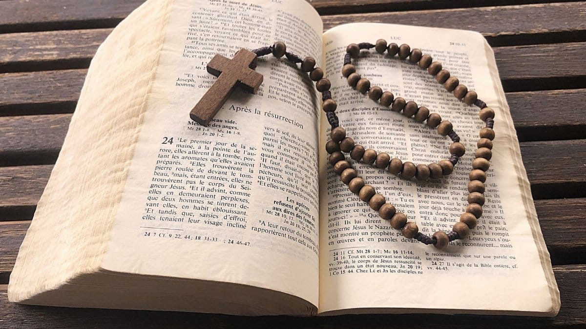 Open Bible with wooden rosary beads, emphasizing faith and spirituality.