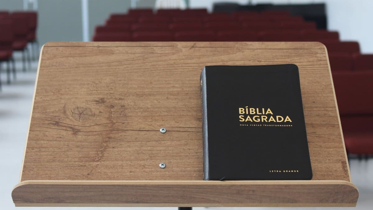 Close-up of a Bible on a wooden lectern in an empty church auditorium.